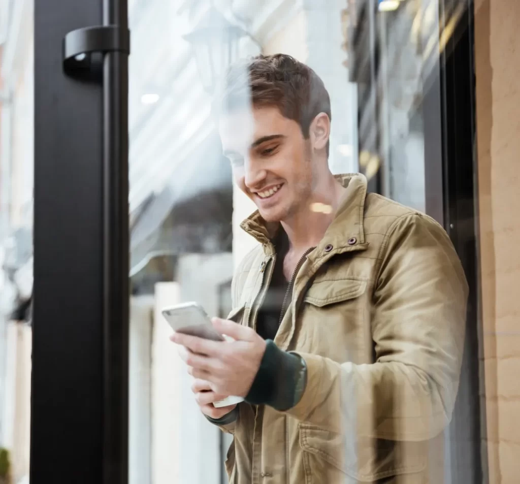 Man Smiling on Street With His Phone
